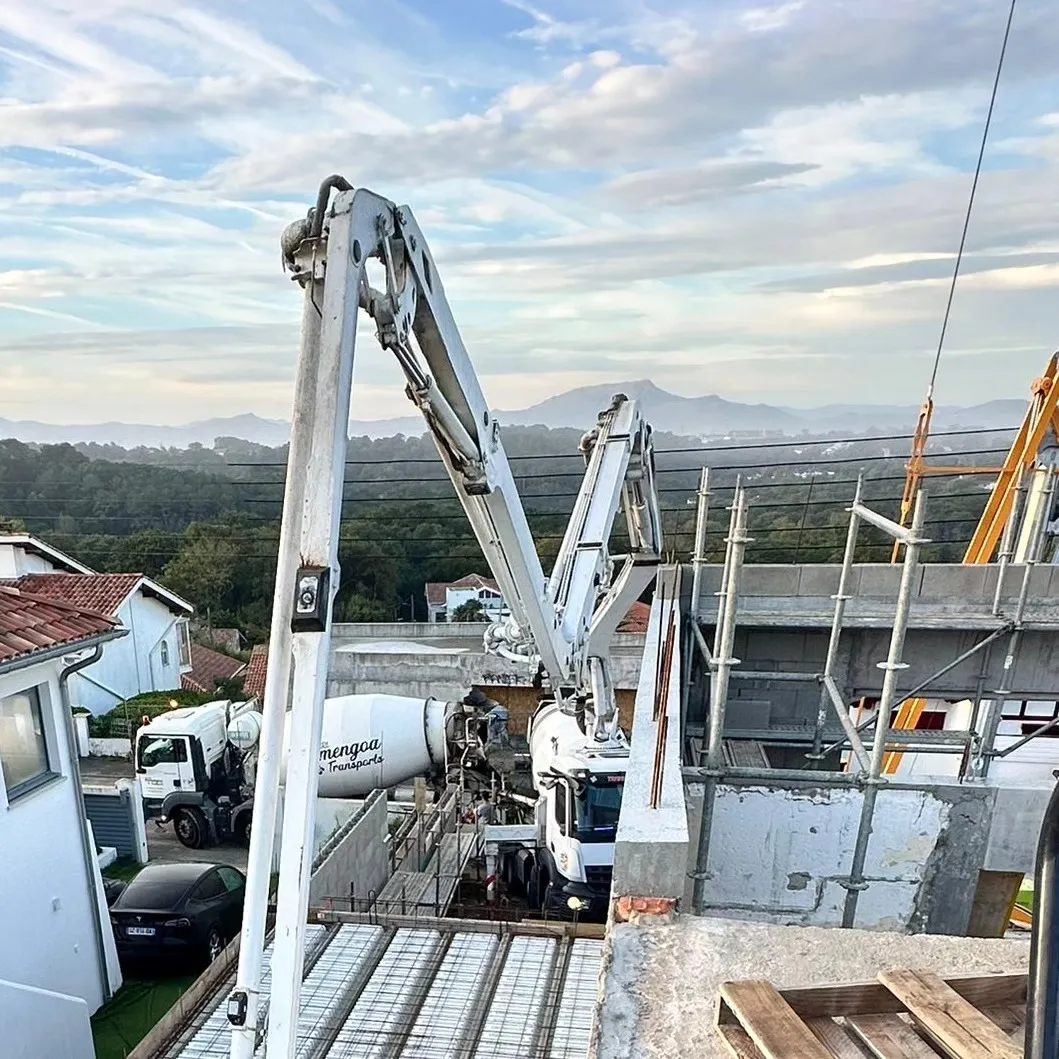 Pompe à béton déployée au-dessus de la villa, vue sur la côte