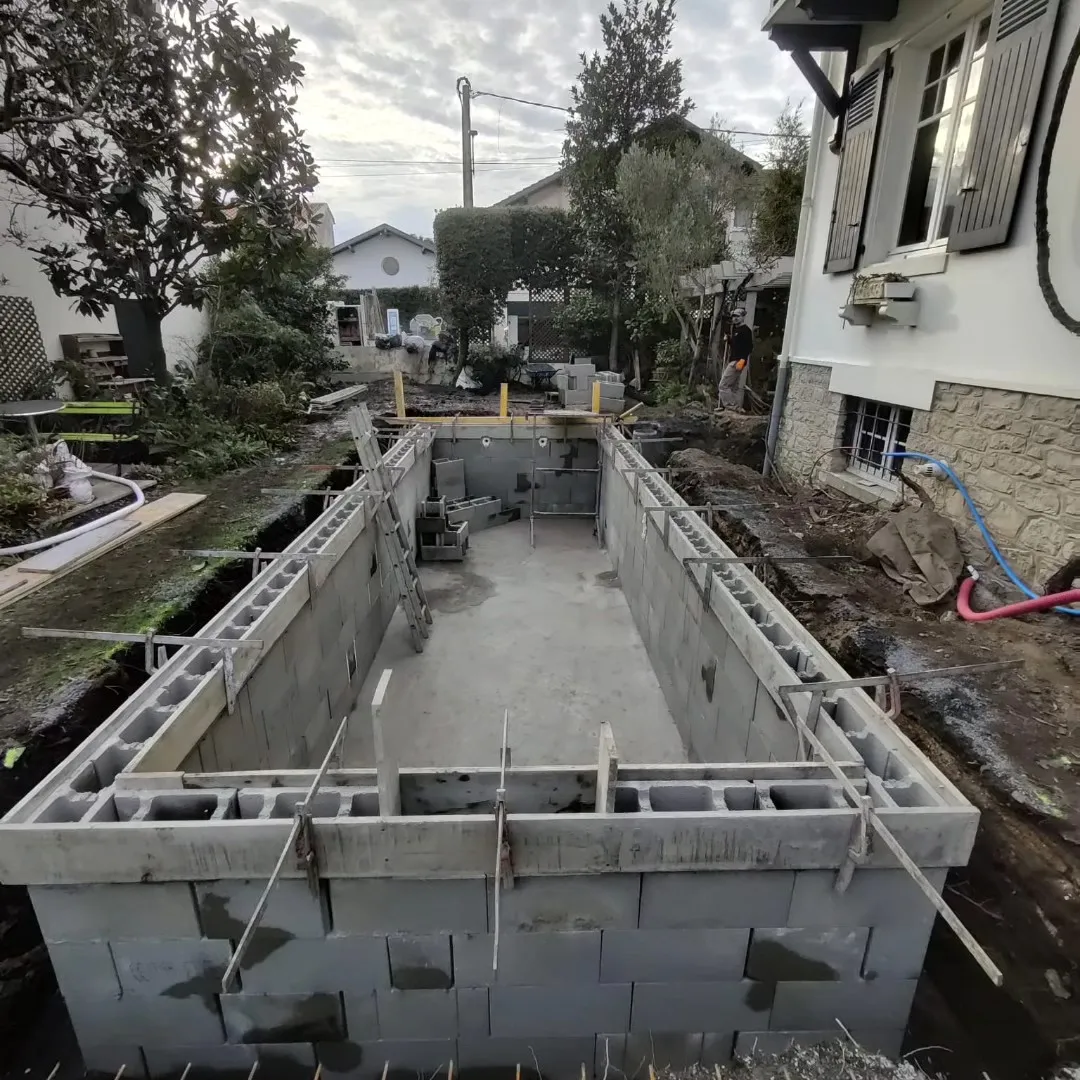 Bassin béton construit entre deux maisons, sur un accès très étroit