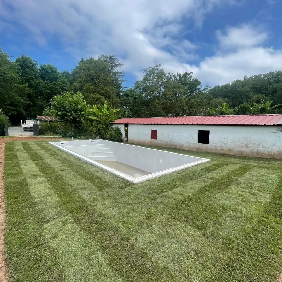 Vue d’ensemble de la piscine et du jardin, maison en arrière-plan