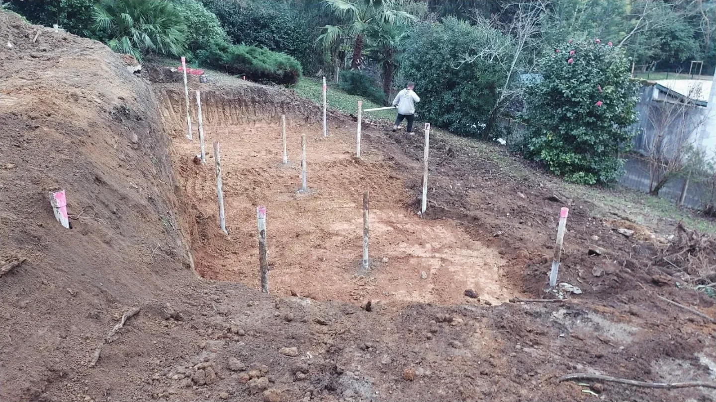 Terrain en pente terrassé et piqueté avant la construction du bassin